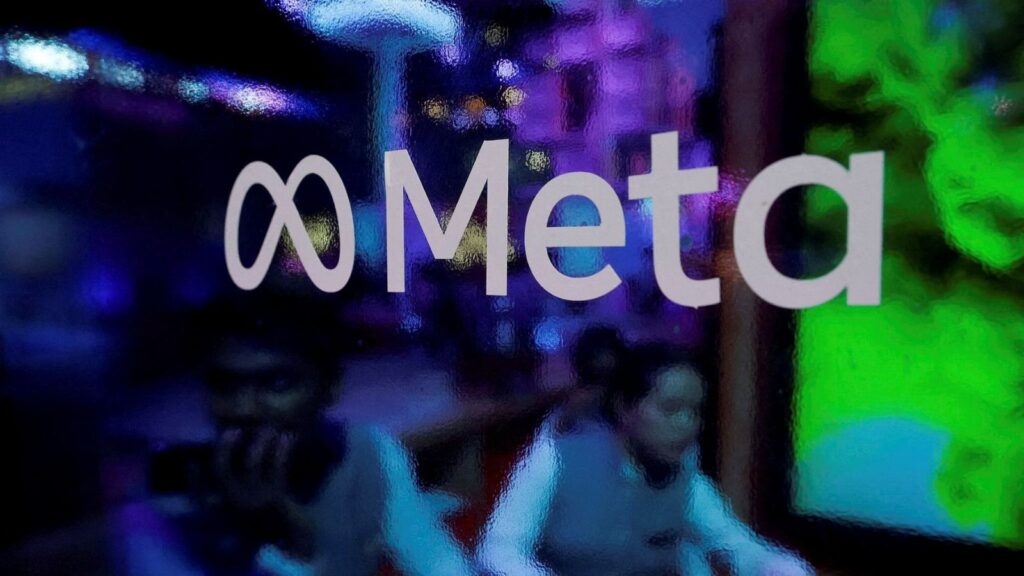 People are seen behind a logo of Meta Platforms, during a conference in Mumbai, India, September 20, 2023.