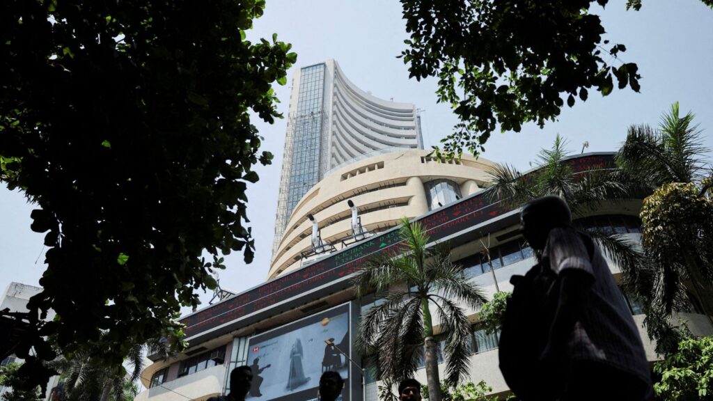 Men walk past a screen displaying market results outside the Bombay Stock Exchange (BSE) in Mumbai
